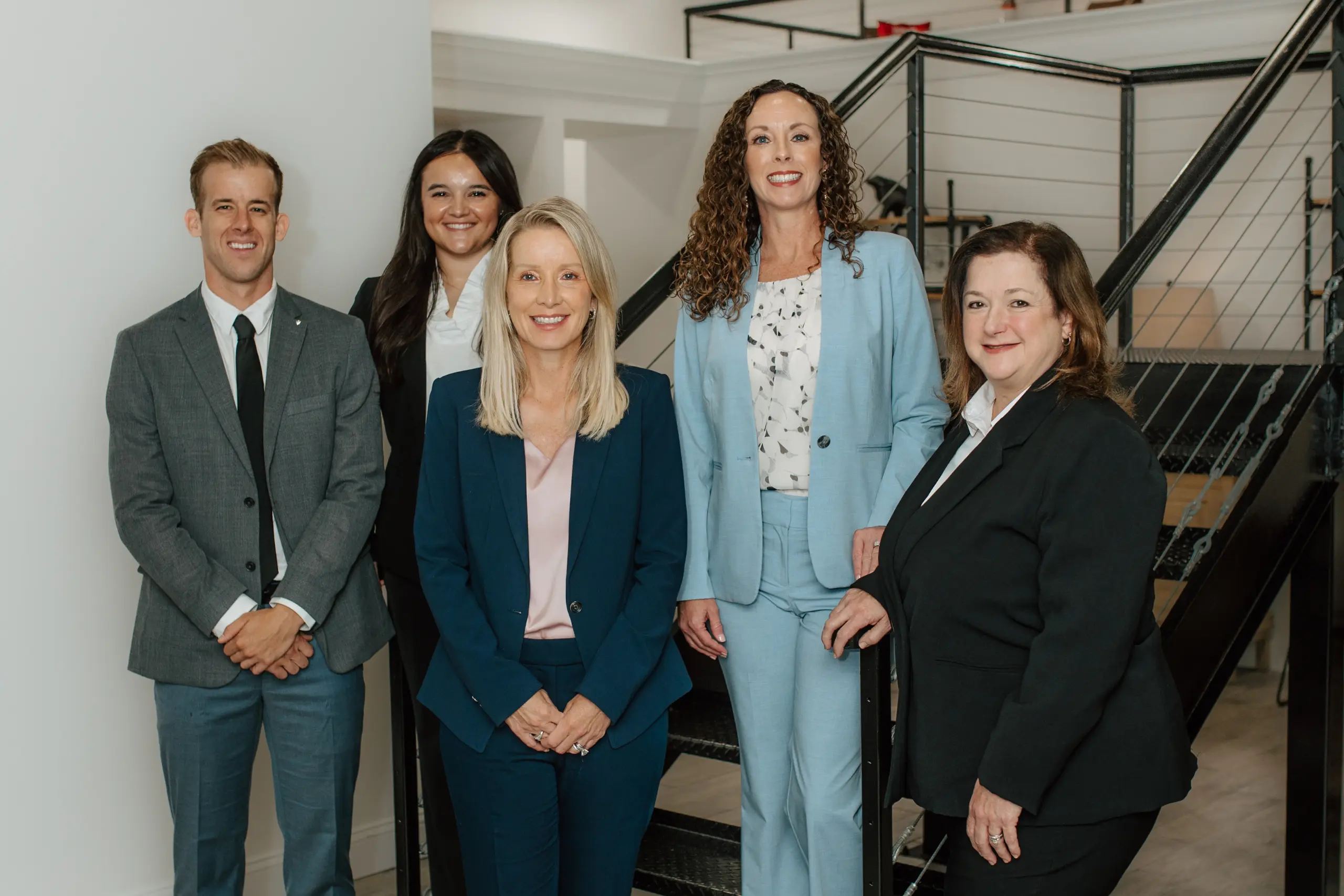 Griffin team of four women and a man beside an office staircase